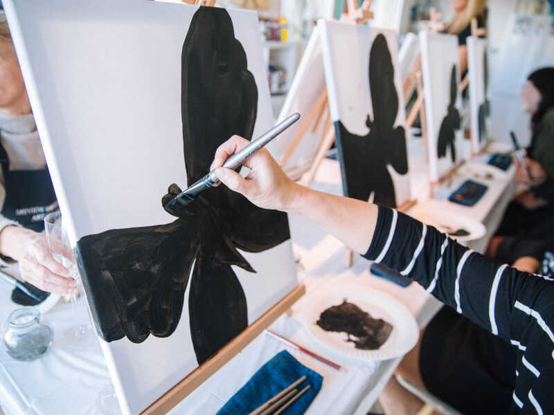 Person painting a black butterfly at a paint and sip